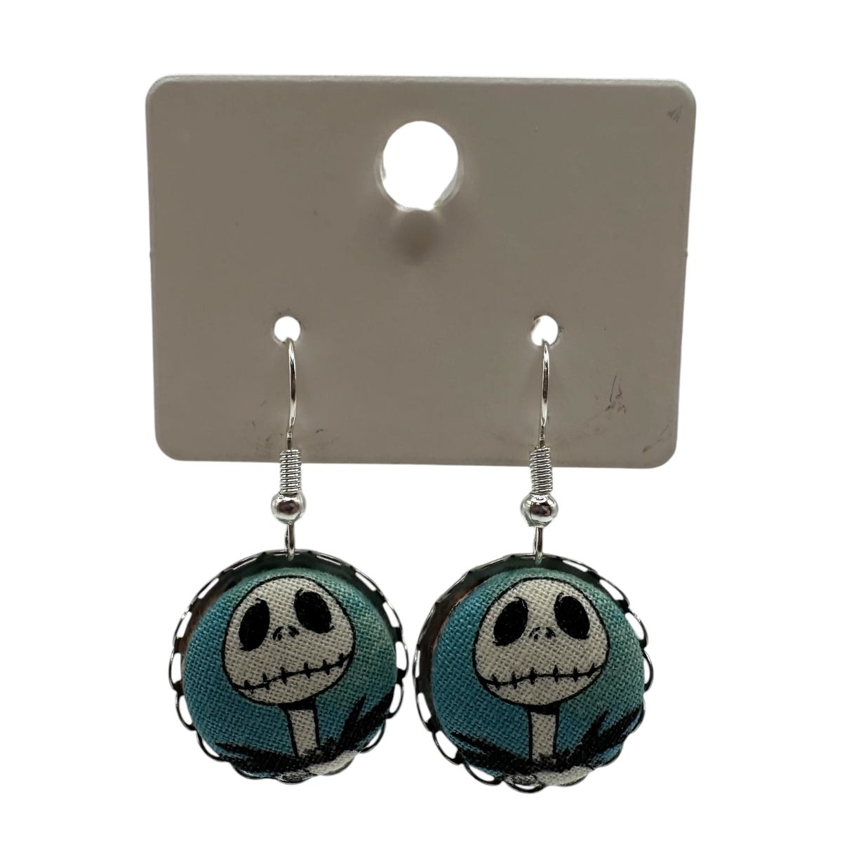 Close up of Jack Skellington drop earrings, scalloped edge silver tone tray
